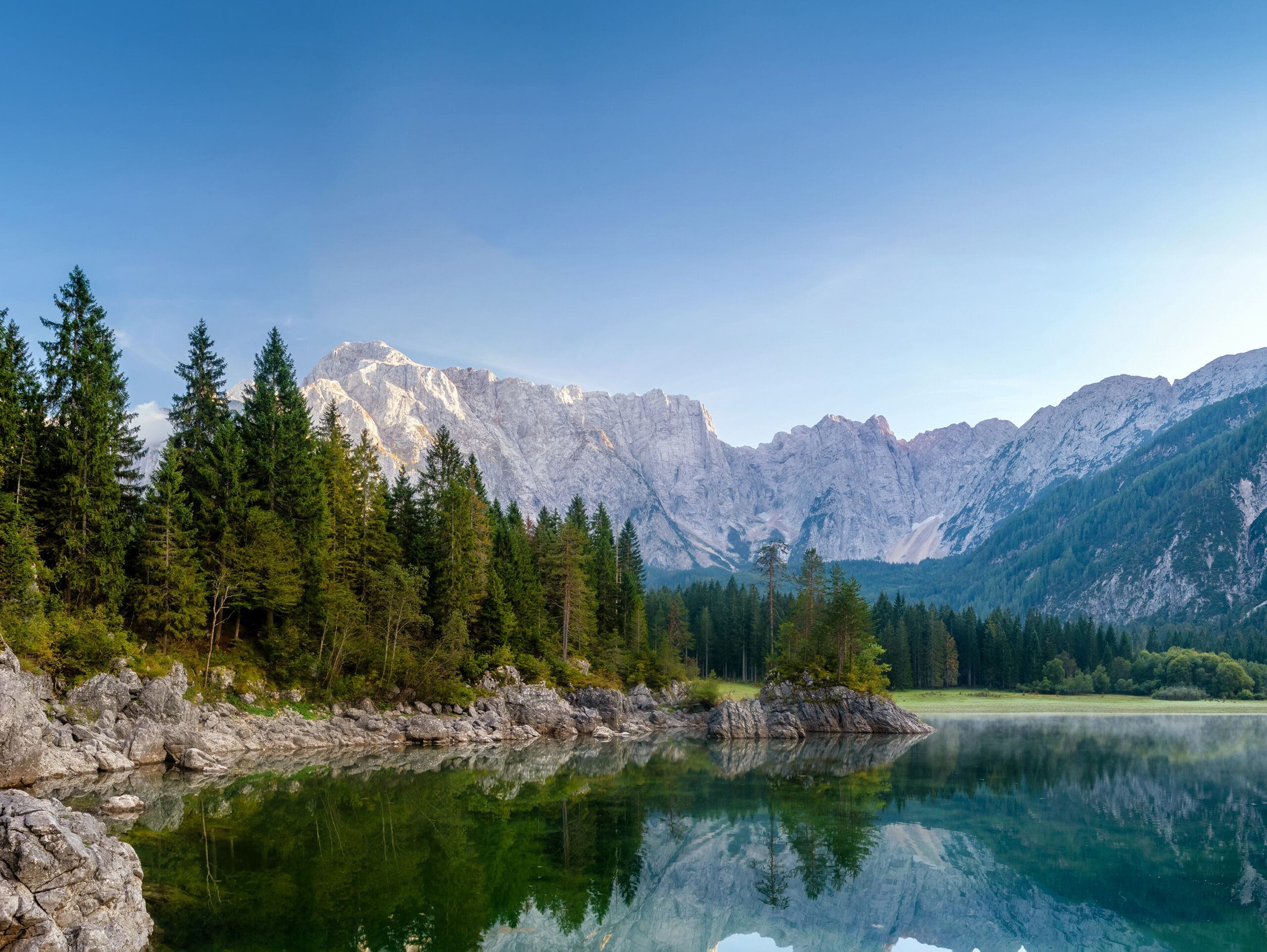 A blue river runs through a lush pine forest, highlighting Kraton's mission of sustainable sourcing and sustainable solutions.